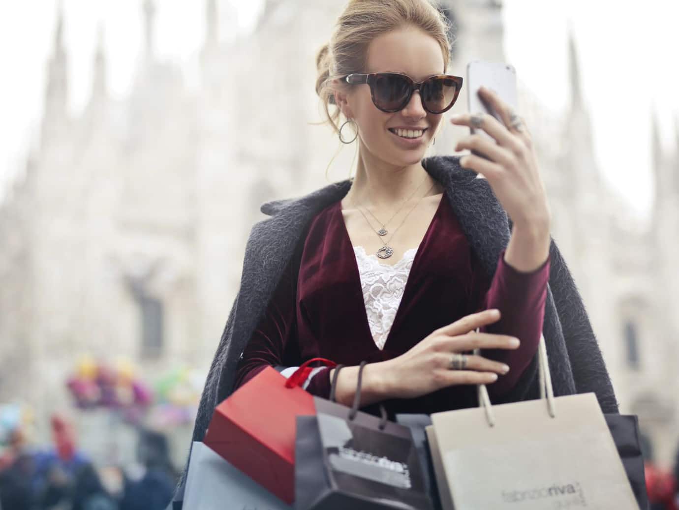 woman carrying shopping bags and looking at her phone 